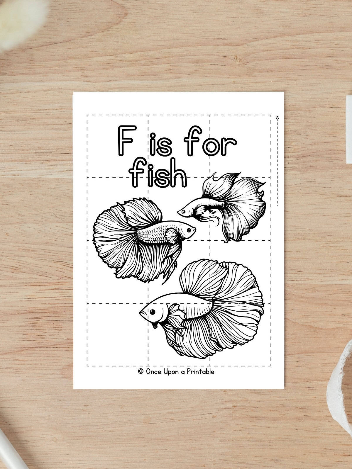 F is for Fish coloring puzzle activity worksheet laying on a wooden table. 