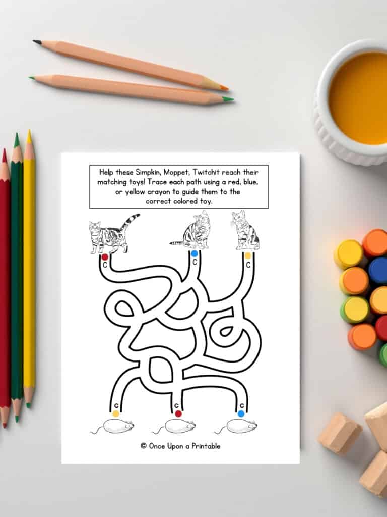 Help the cats find their toys a fun maze activity laying on a table with coloring pencils.
