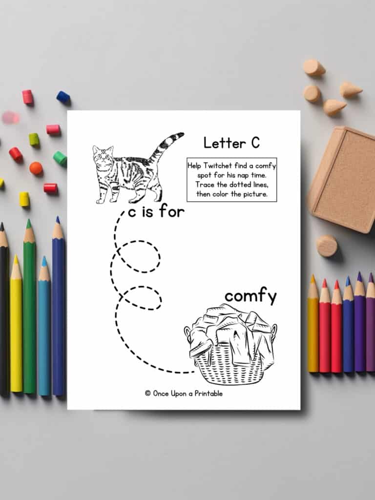 Letter c line tracing and coloring page with a cat laying on a table with coloring pencils.