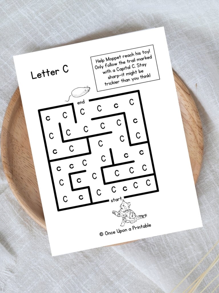 Letter C maze cat toy worksheet laying on a wooden lazy Susan on a white tablecloth.