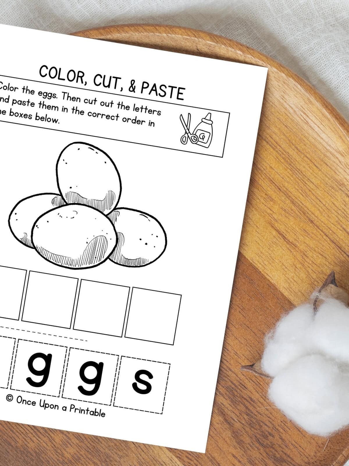 Letter E color, cut, and paste activity sheet with eggs laying on a wooden lazy Susan.