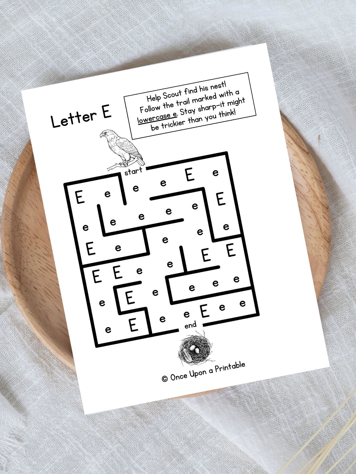 Letter E maze Eagle and nest worksheet laying on a wooden lazy Susan on a white tablecloth.