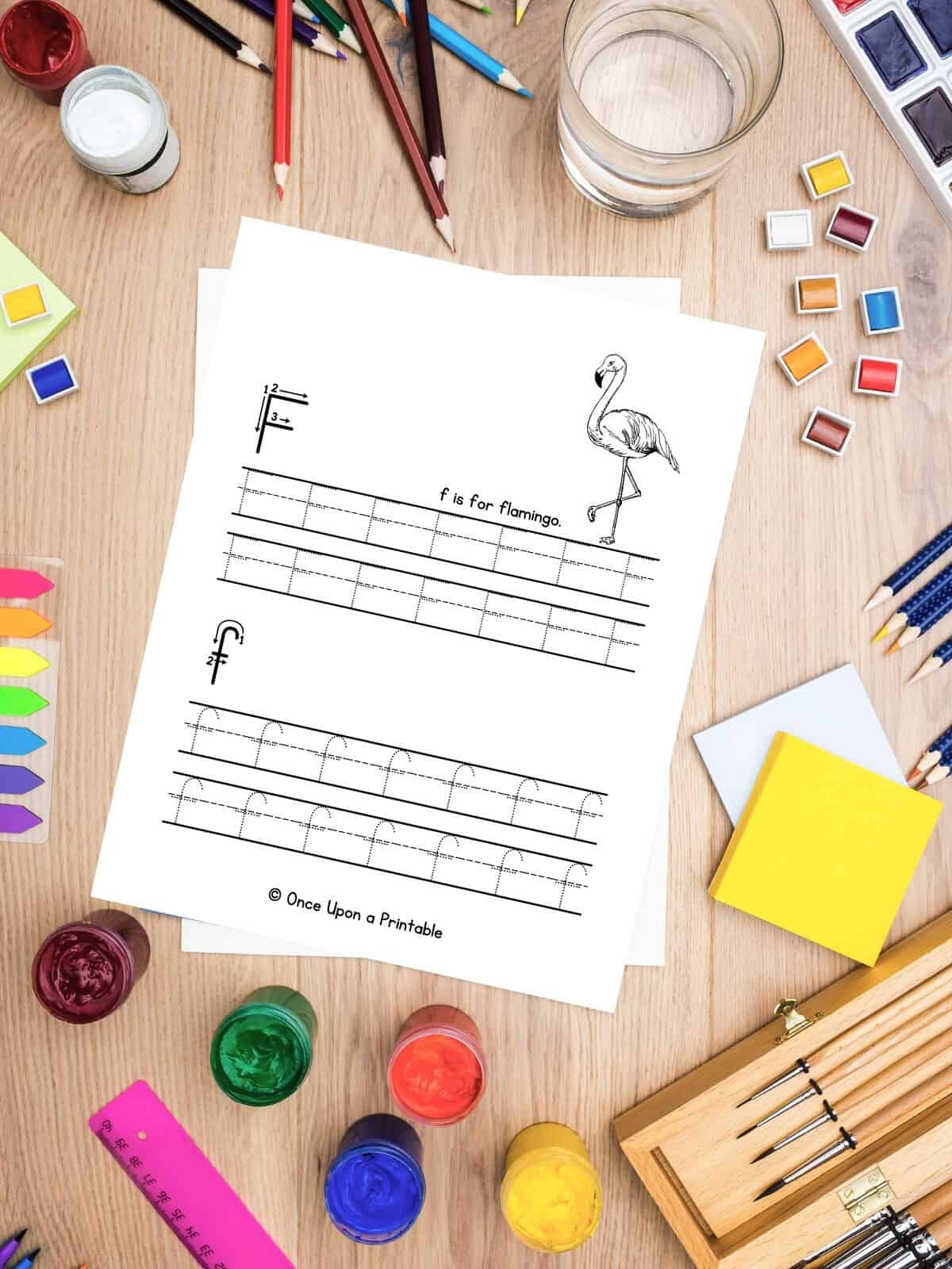 Letter F is for Flamingo letter practice with capital F and lowercase f laying on a table with chaotic art supplies.