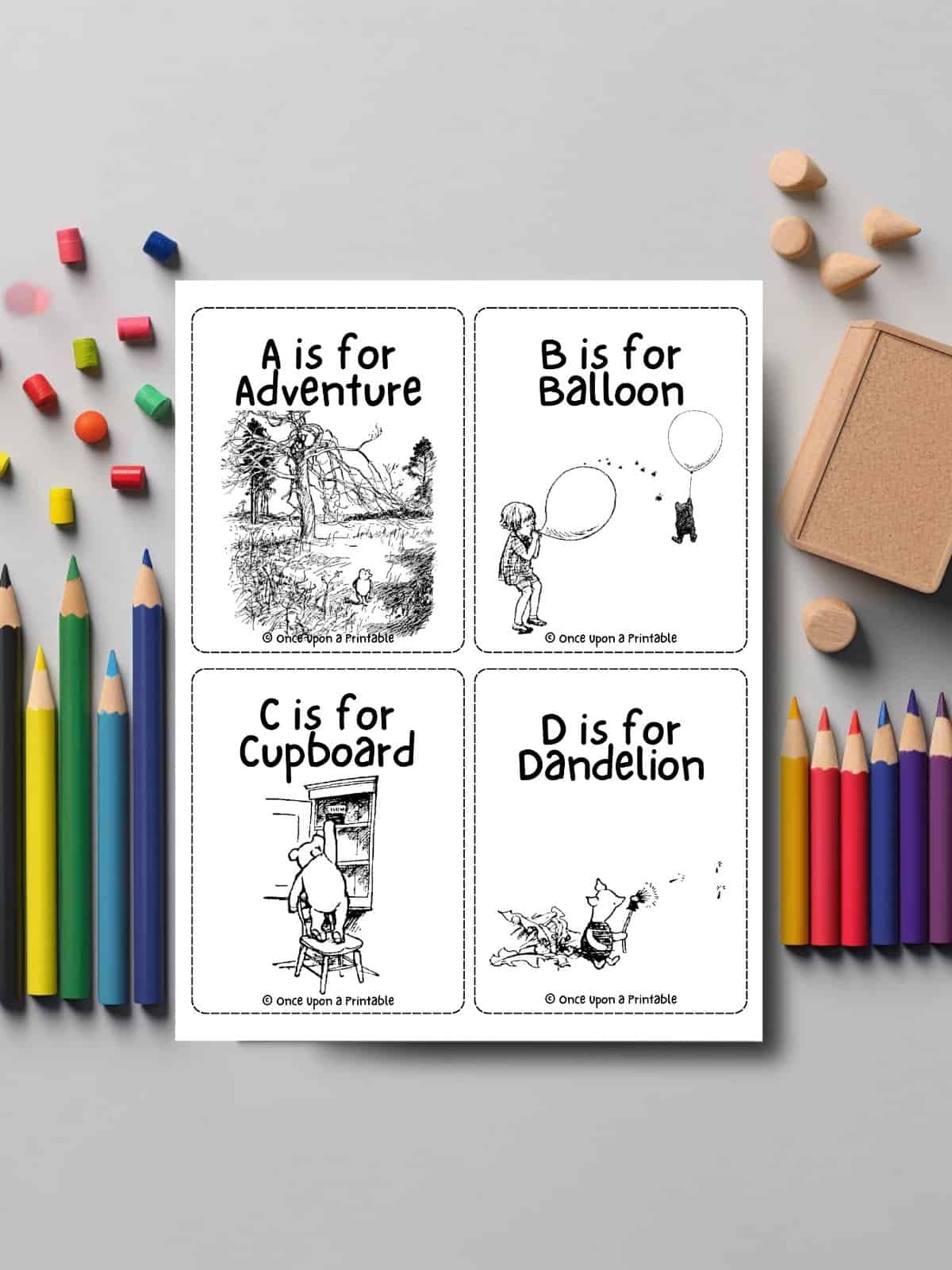 Alphabet flashcards featuring winnie the pooh illustrations laying on a table with coloring pencils. 