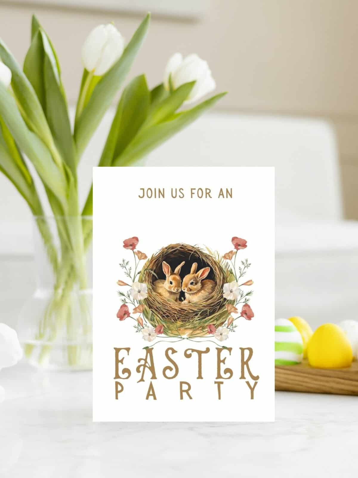 baby bunny easter invitation card printable laying on a table with vase of tulips.