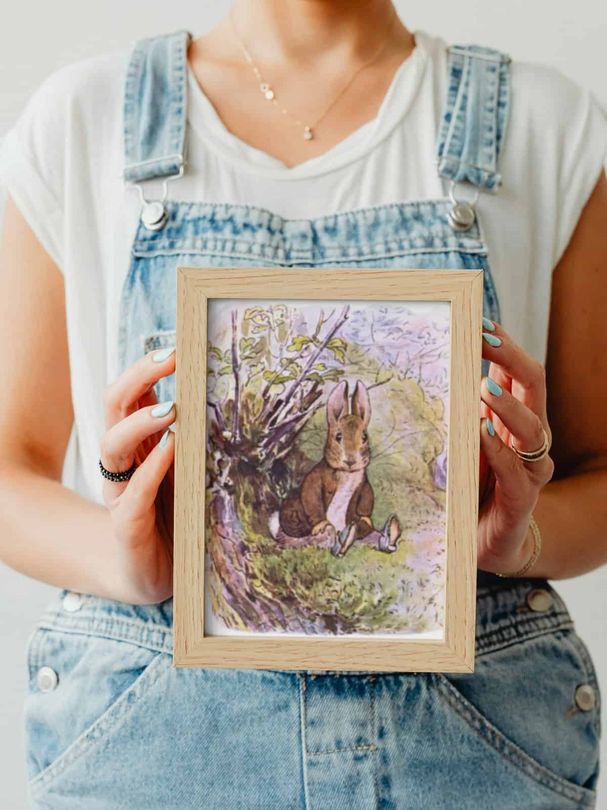 An illustration from the tale of benjamin bunny framed and held in the arms of a woman.