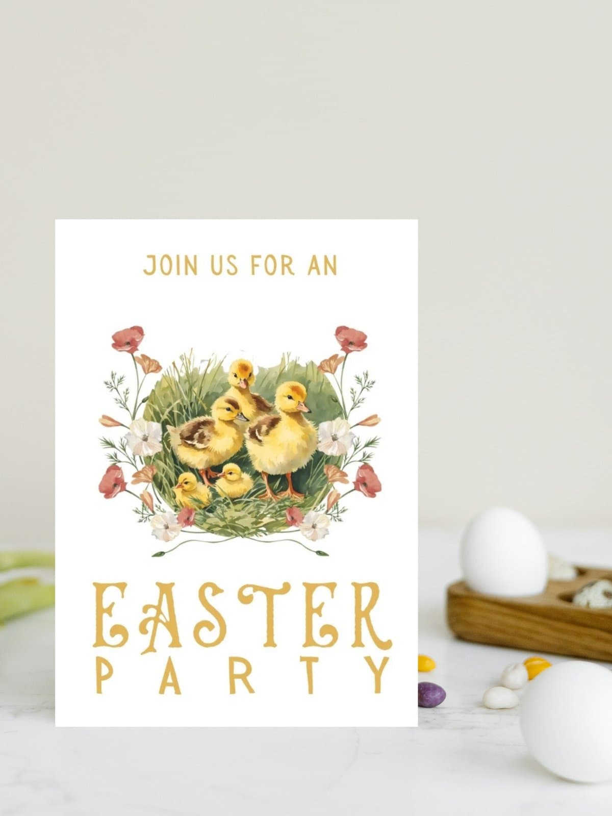 Duckling easter party invitation card printable sitting on a white table with a carton of eggs.