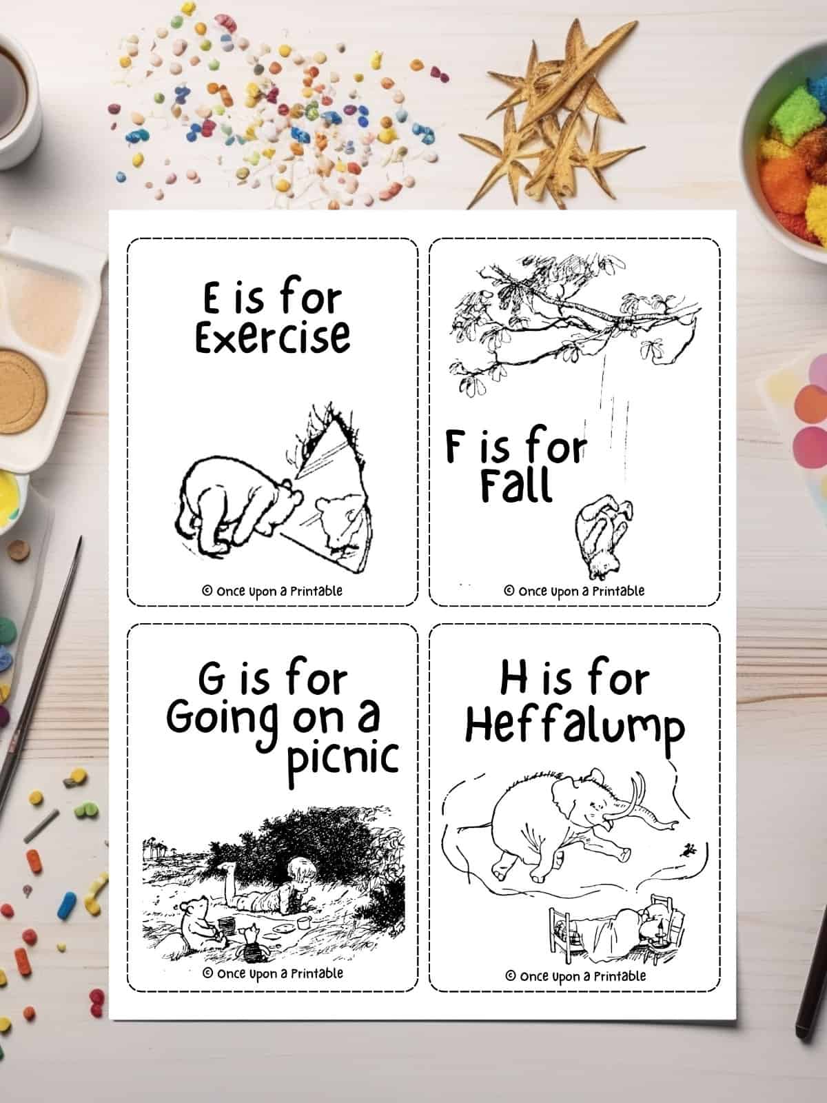 Alphabet flashcards featuring winnie the pooh illustrations laying on a table with coloring pencils and glitter.