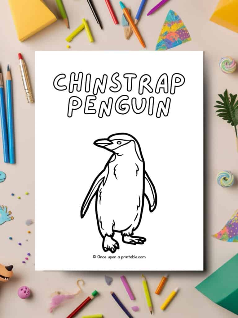 C is for Chinstrap Penguin coloring page laying on a table with art supplies strewn about. 