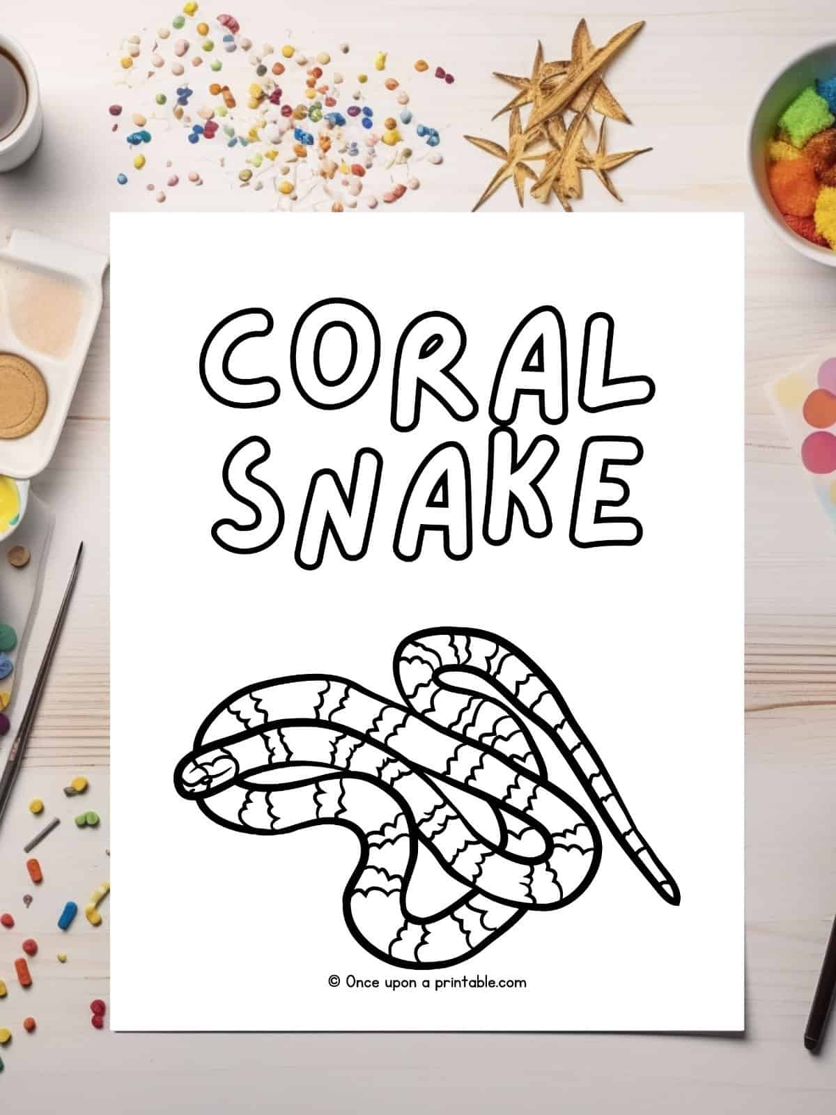 C is for Coral snake coloring page laying on a table.