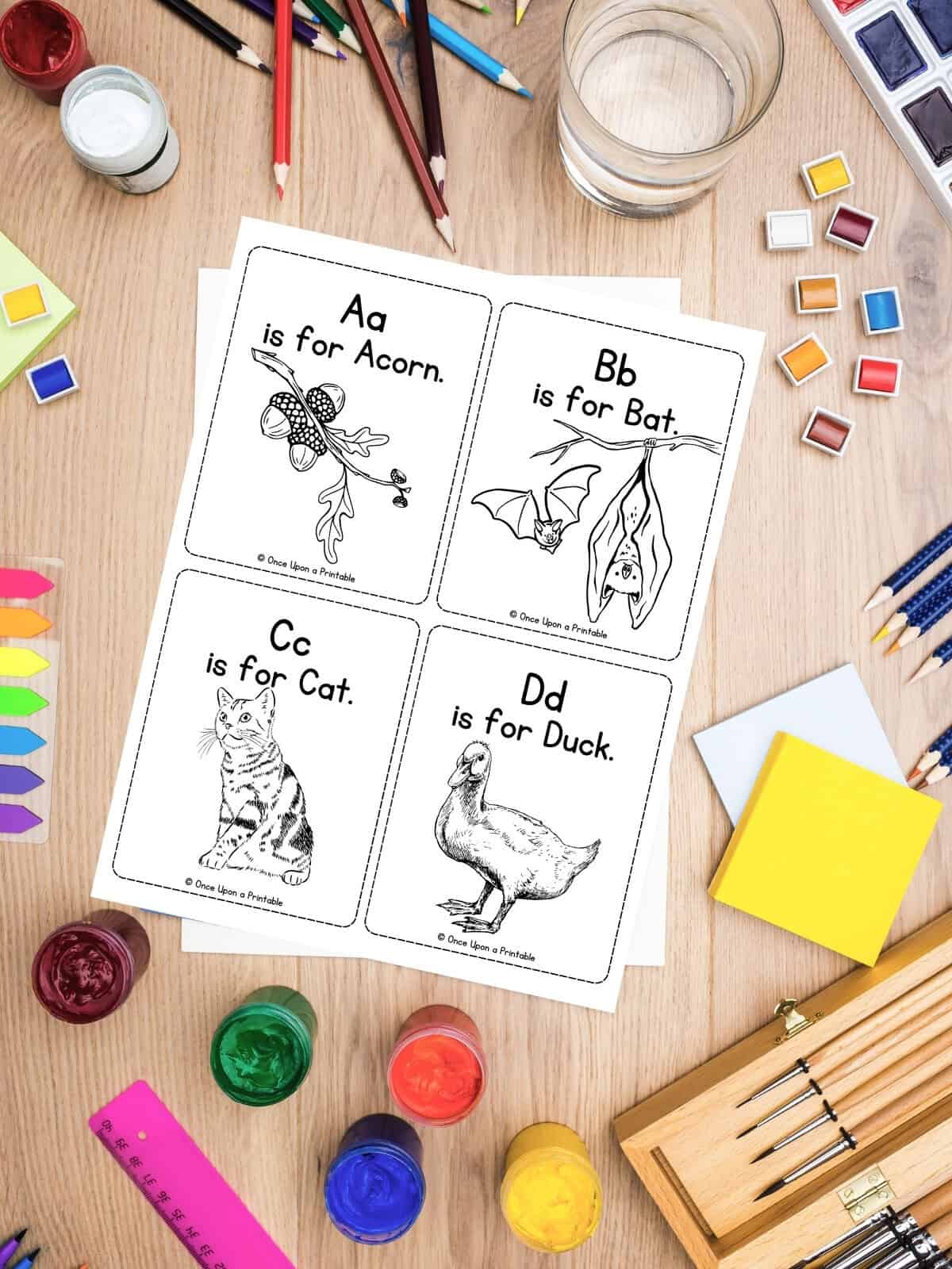 Coloring alphabet flashcards laying on a table with coloring supplies.