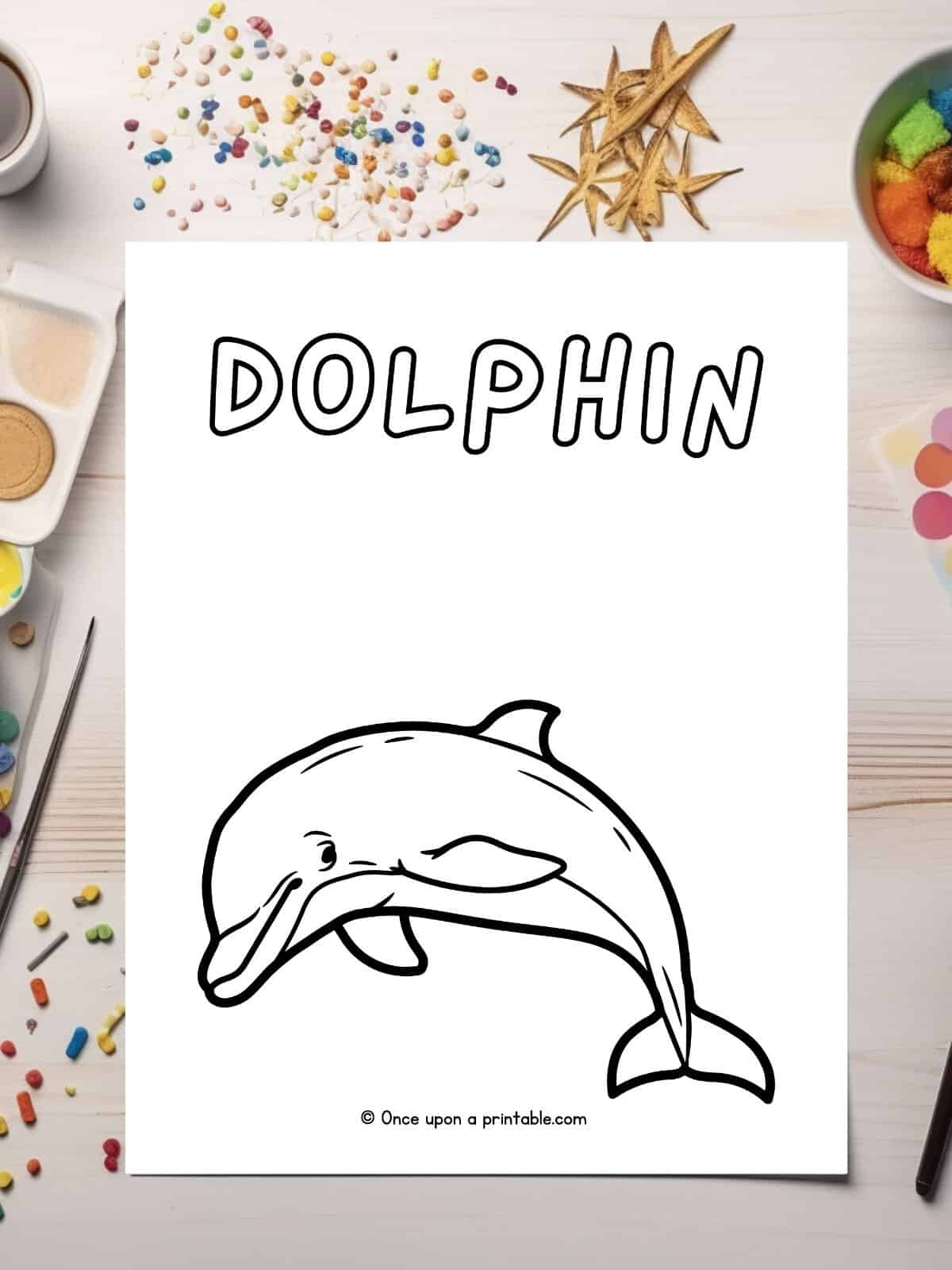 D is for Dolphin coloring page laying on a table with glitter.