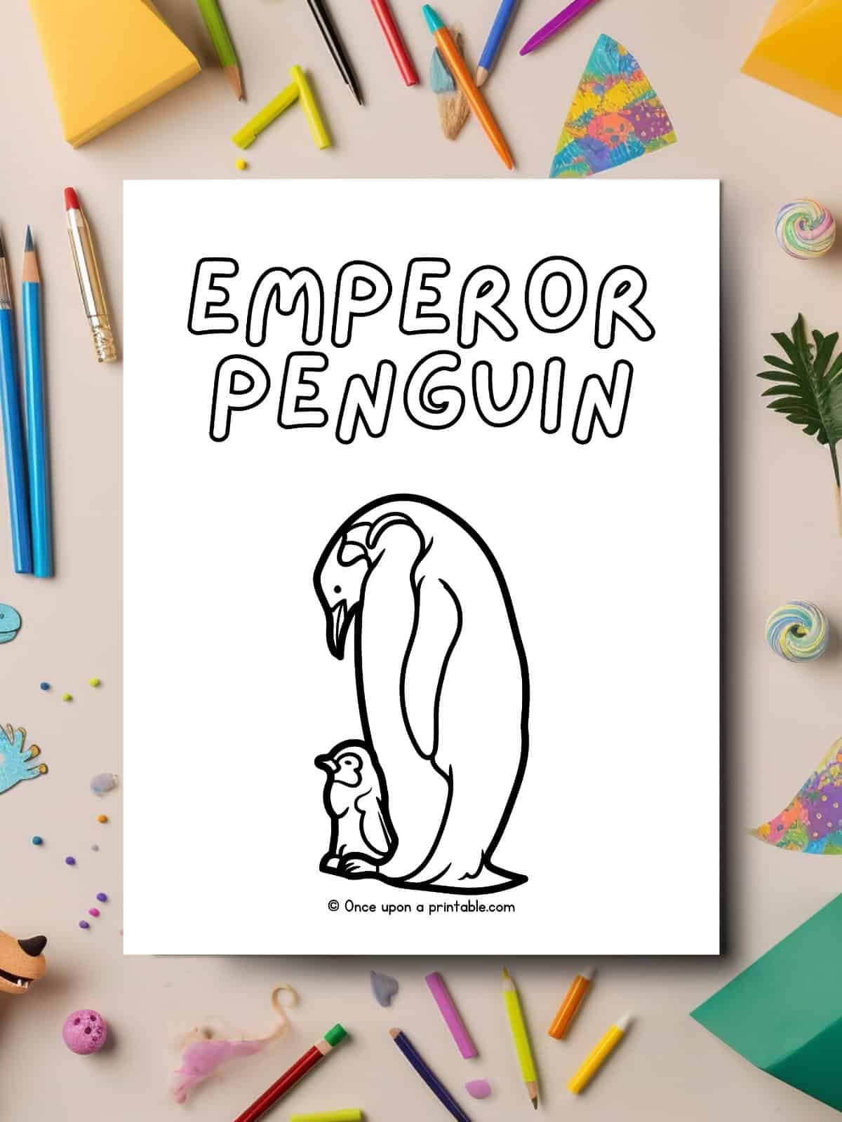 E is for Emperor Penguin animal coloring page laying on a table covered in art supplies. 
