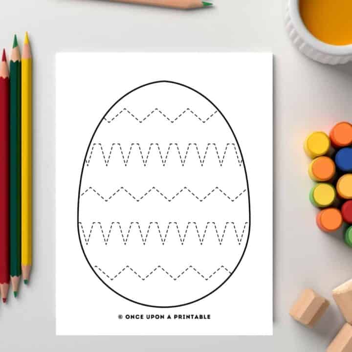 Easter egg tracing pages with zig zags laying on a table with coloring supplies.