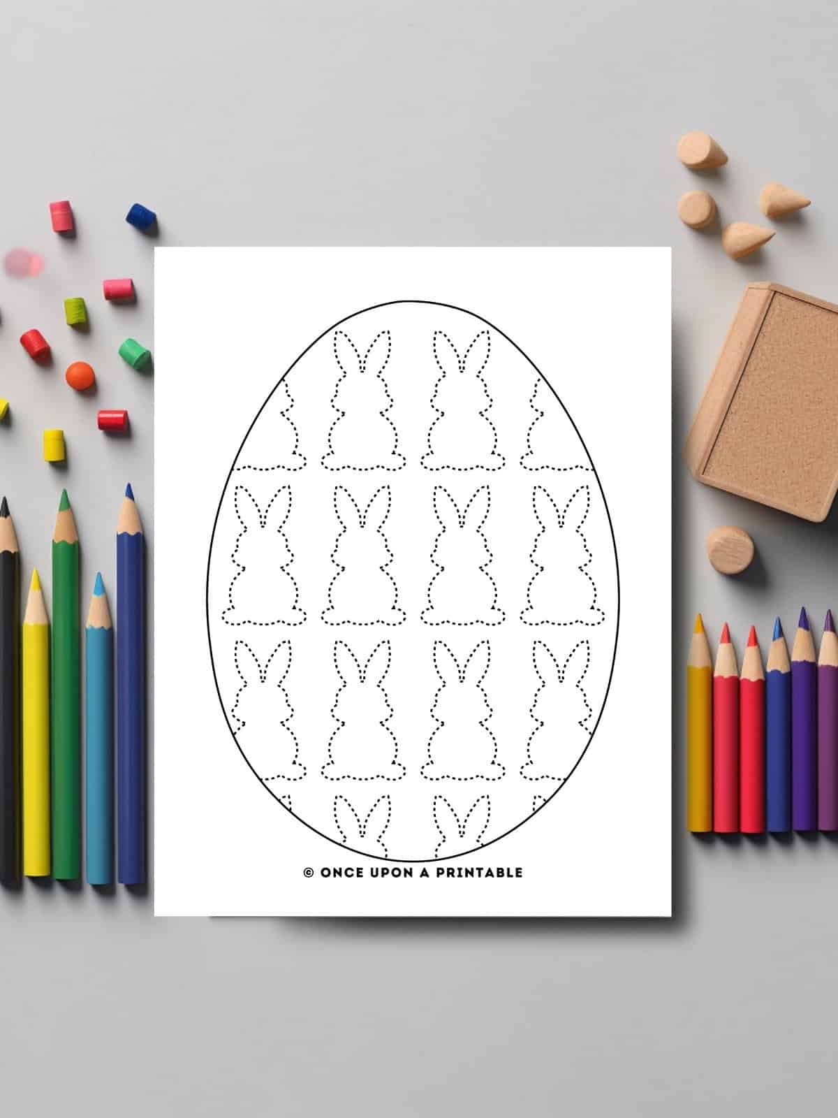 Easter egg tracing worksheet with peep bunnies laying on a table with coloring pencils.