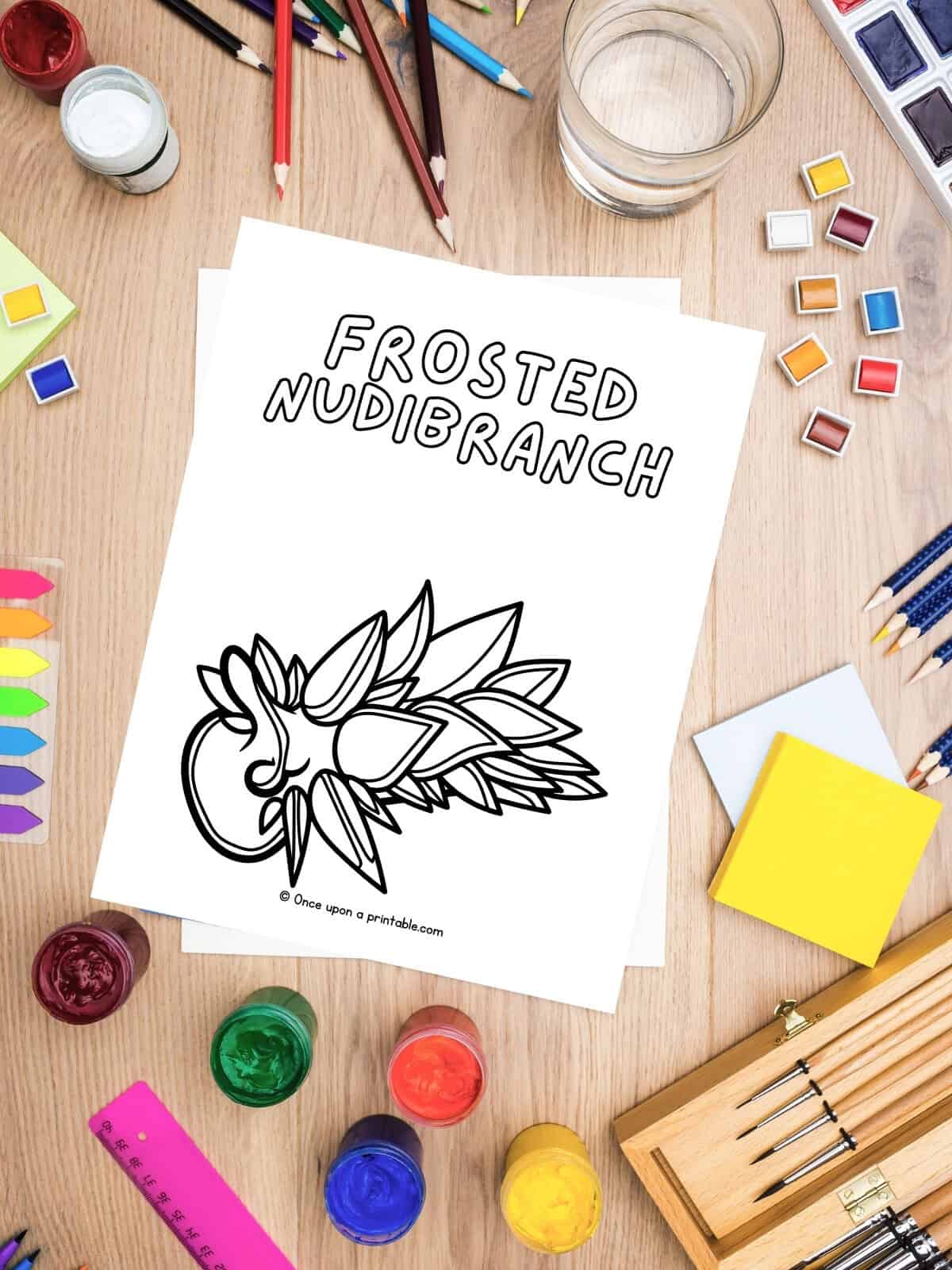 F is for Frosted Nudibranch animal coloring page on a table with coloring supplies. 