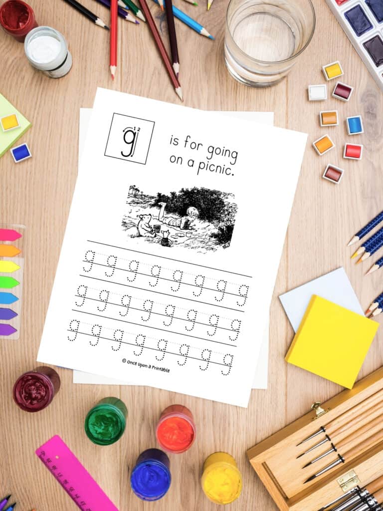 G is for going on a picnic classic Pooh tracing letter "g" worksheet laying on a table with lots of art supplies.