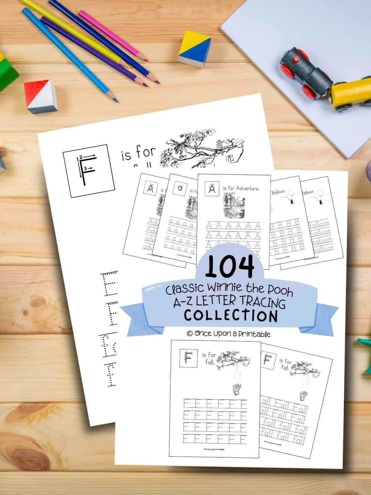 Winnie the Pooh A-Z letter tracing worksheets laying on a wooden table with coloring pencils and a wooden train.