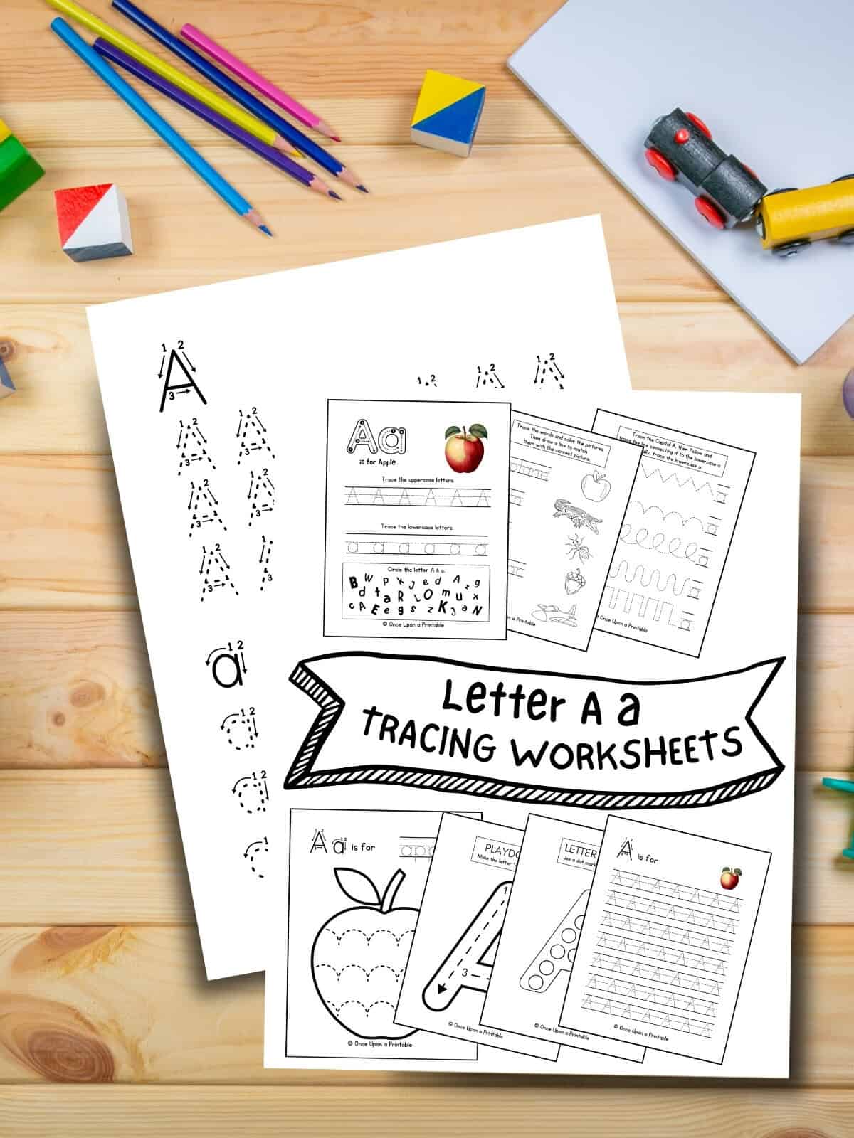 Letter A tracing worksheet collection cover page laying on a wooden table with toys and pencils. 