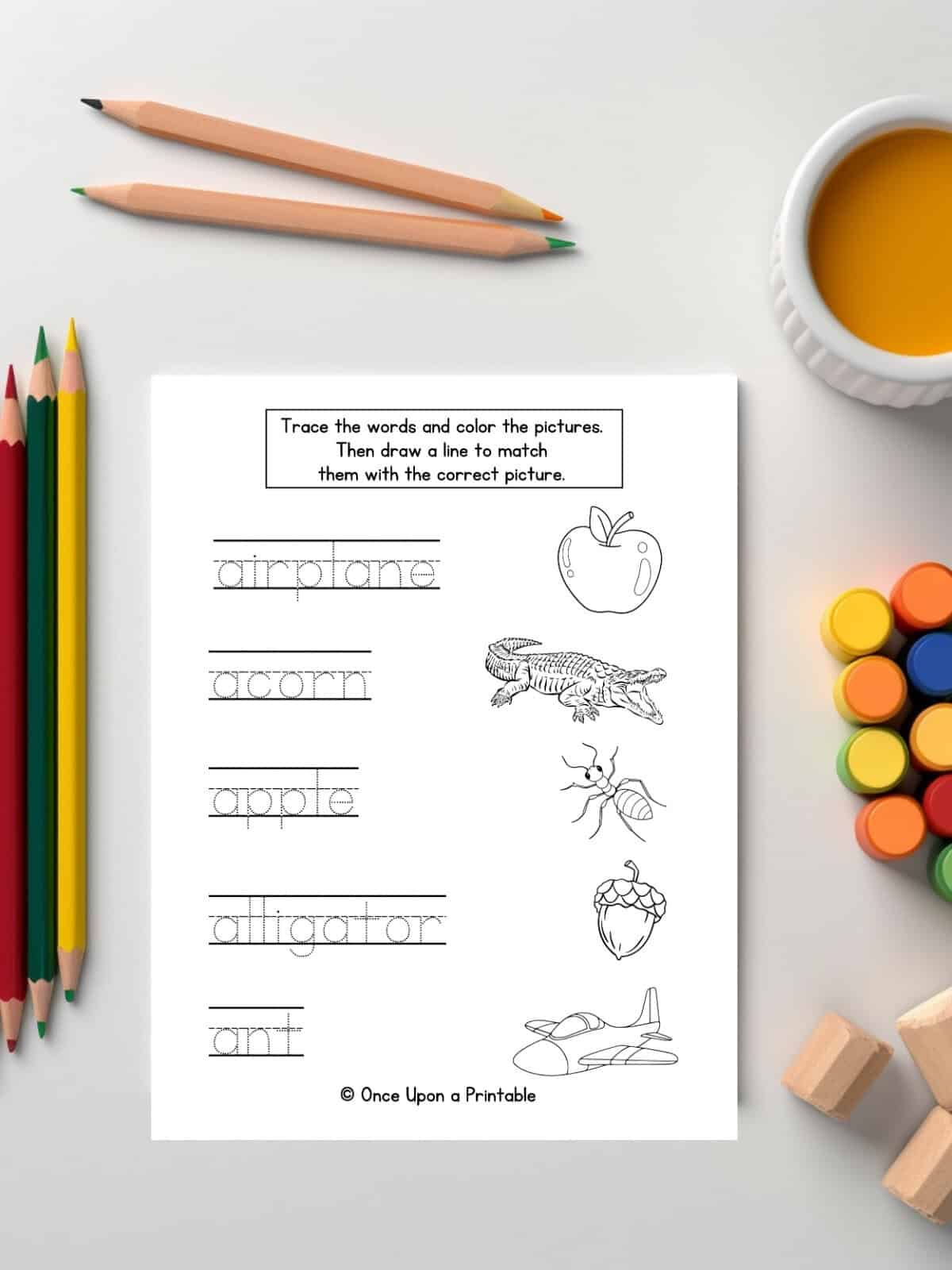 A is for word tracing and picture matching worksheet for kids laying on a table with coloring pencils.