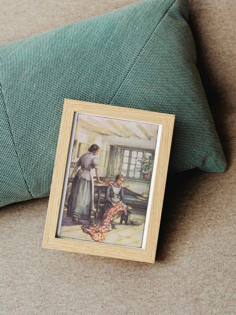 Full color illustration of Anne Shirley and Marilla Cuthbert framed and laying on a green pillow.