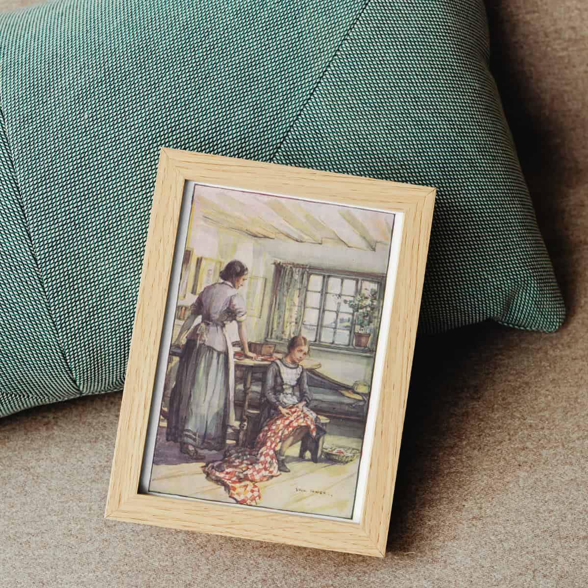 Full color illustration of Anne Shirley and Marilla Cuthbert framed and laying on a green pillow.
