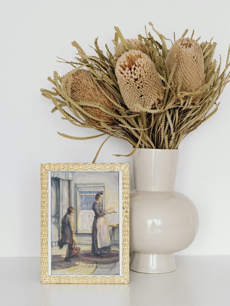 Anne Shirley and Marilla cuthbert illustration by sybil Tawse in a small golden frame next to a vase.