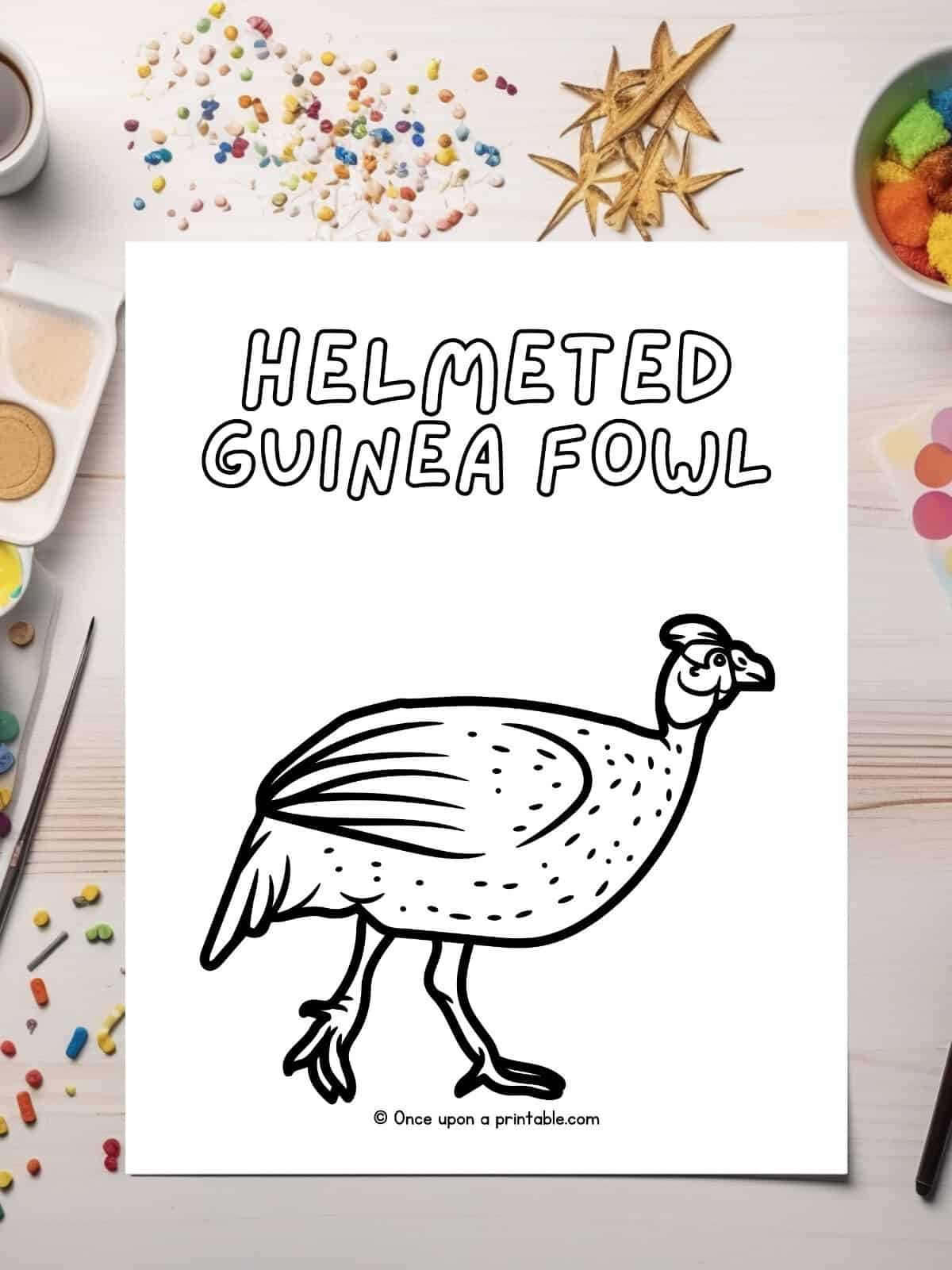 h is for Helmeted Guinea fowl coloring page laying on a table with glitter.