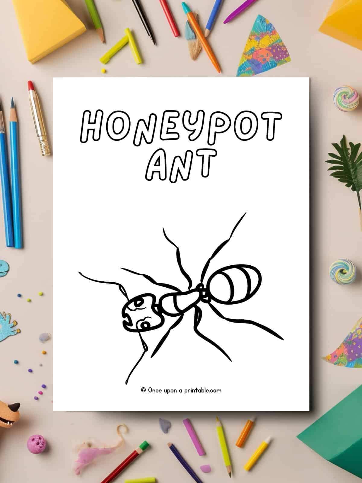 Honeypot ant coloring page laying on a messy table with coloring supplies. 