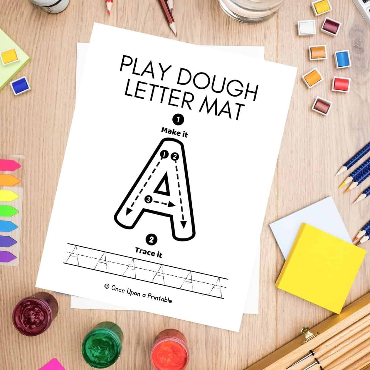 A tracing playdough mat laying on a table with art supplies.