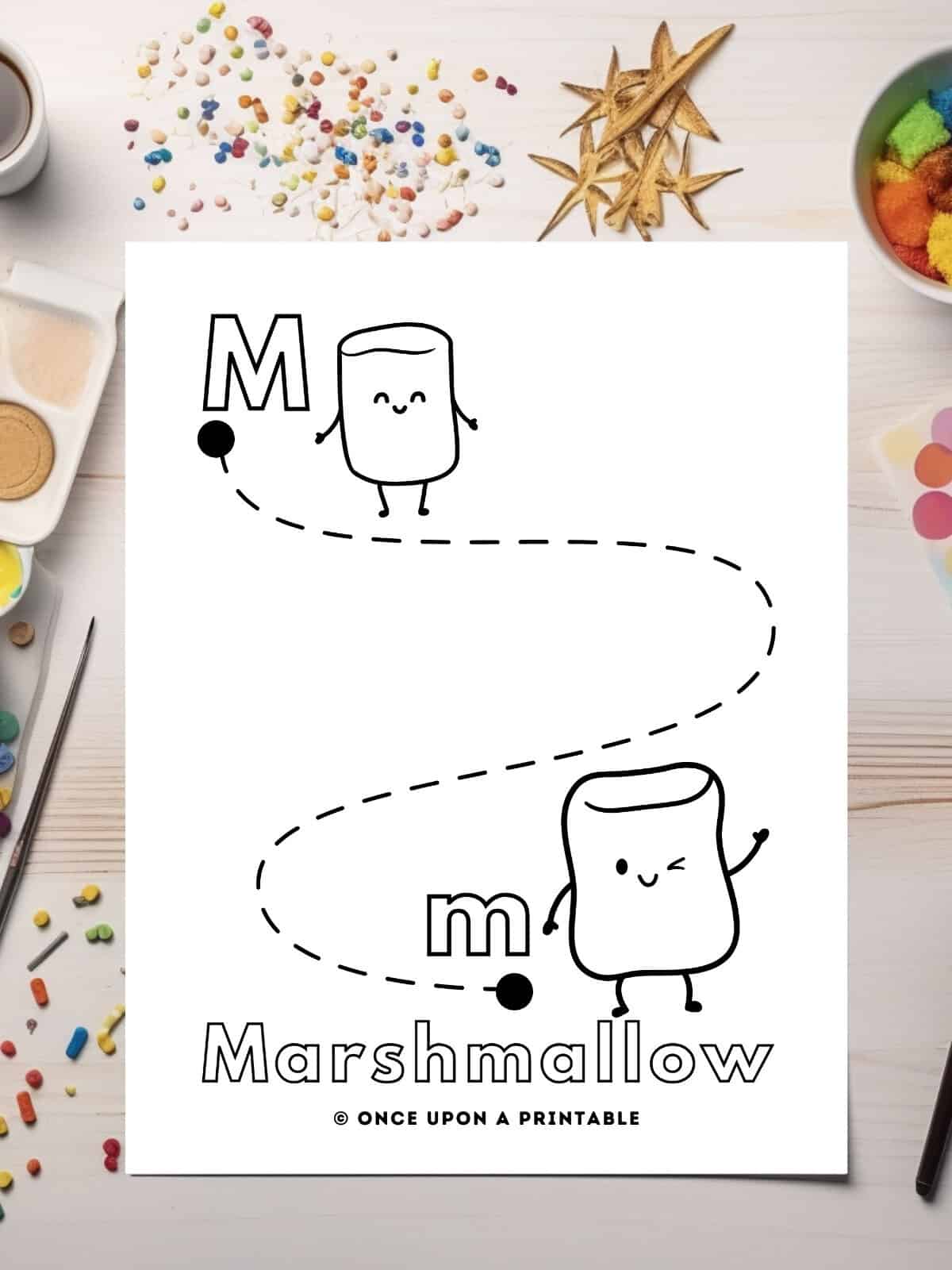 M is for Marshmallow Kawaii style graphics on a line tracing worksheet laying on a table with glitter.
