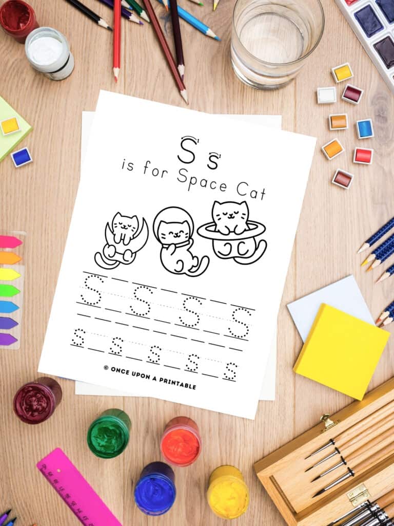 S is for Space cat letter tracing page for kids to color laying with art supplies. 