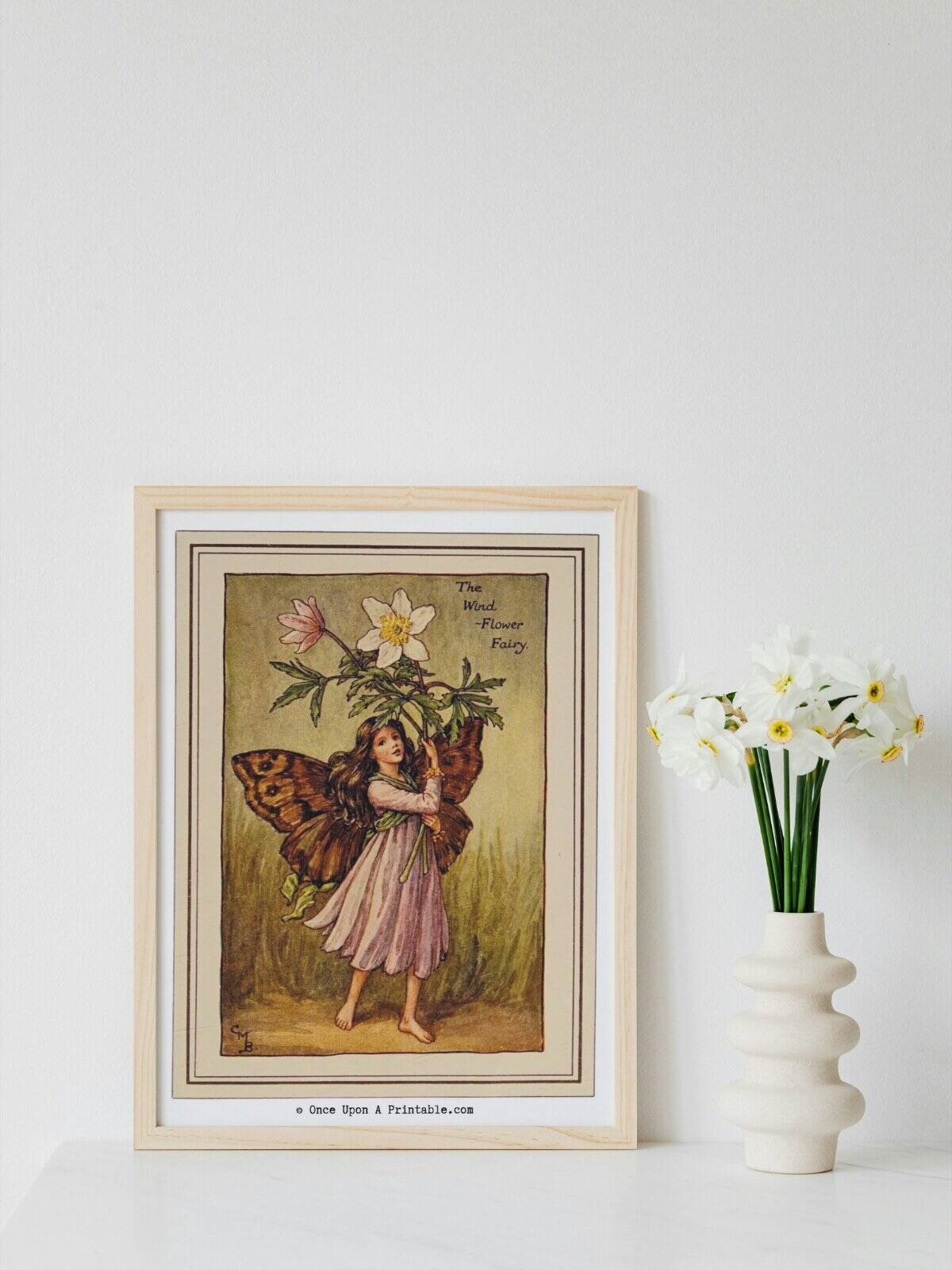 Cicely Mary Barker's spring flower fairies art prints framed next to a vase of daffodils.