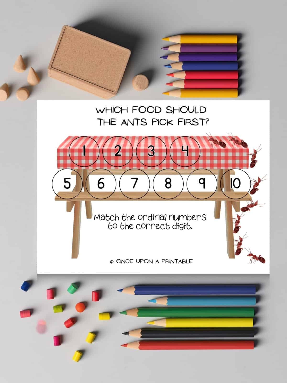The ordinal number ants picnic game board laying with coloring pencils. 
