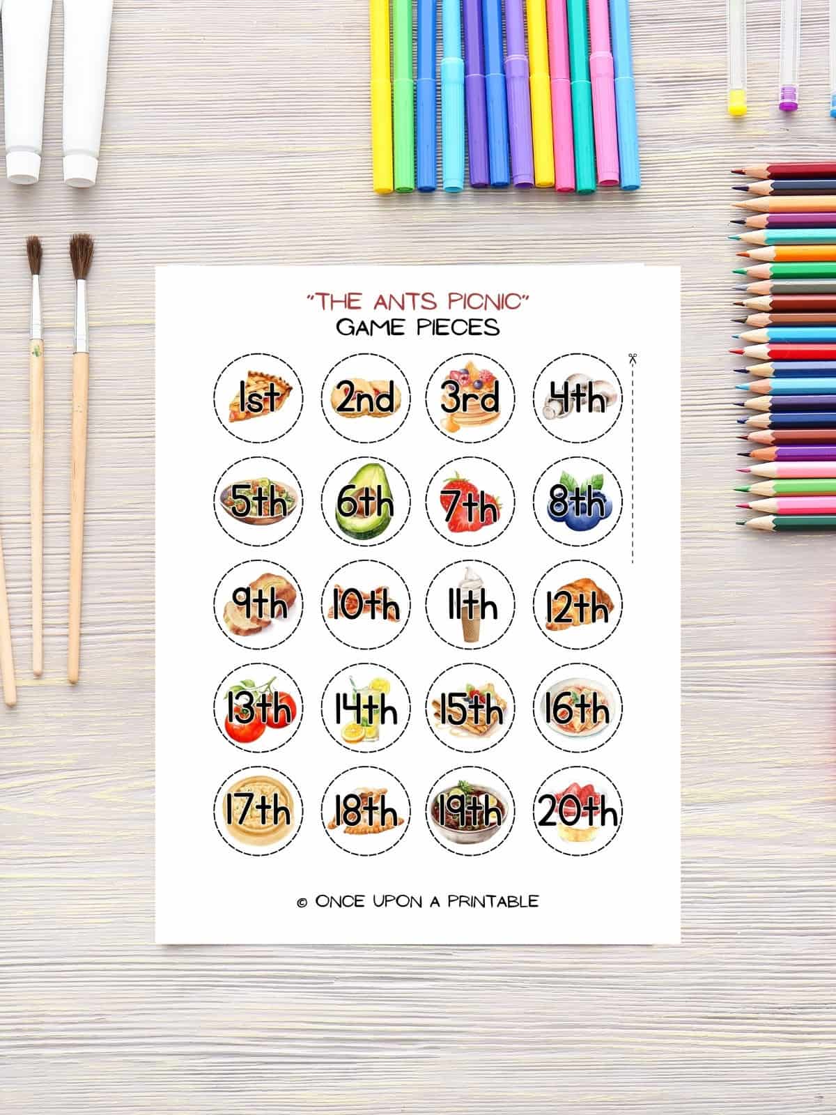 The Ants picnic game pieces with ordinal numbers laying on a table with coloring tools. 