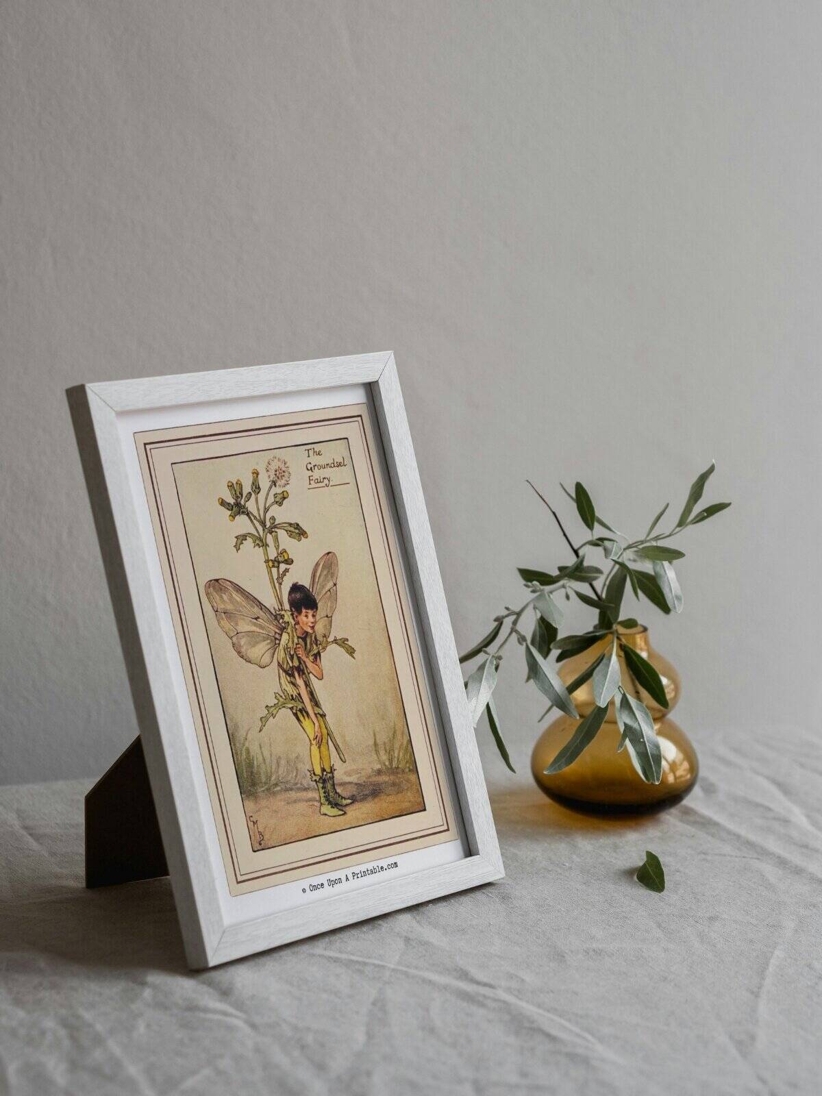 The Groundsel Flower fairy illustration framed in a small frame next to a bud vase. 
