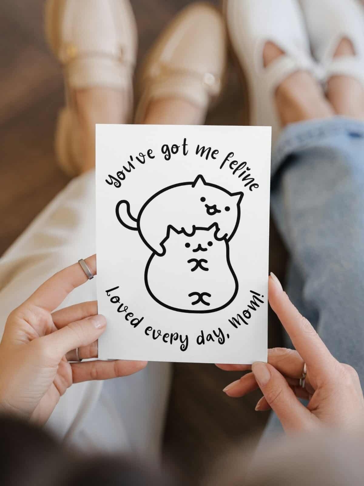 Two cats feline mother's day coloring card being held by a woman. 